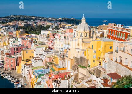 Lebendige farbenfrohe Gebäude und die Kuppel von Santuario di Santa Maria delle Grazie auf den Klippen der Insel Procida, Italien, mit Blick auf das Meer. Stockfoto