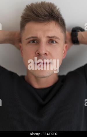 Männliches Nahaufnahme-Porträt. Hübscher junger Mann mit Frisur liegend und in die Kamera schauend Stockfoto