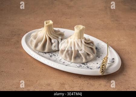 Khinkali-Teigtaschen auf Teller mit Gewürzen Nahaufnahme Stockfoto