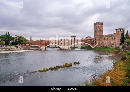 Atemberaubender Herbstblick auf die Scaliger-Brücke und Castelvecchio in Verona. Die Etsch fließt unter majestätischen roten Backsteinbögen, eingerahmt von warmen Farben Stockfoto