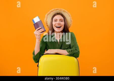 Happy Traveler mit Koffer und Reisedokumenten bereit für Abenteuer in heller Umgebung Stockfoto