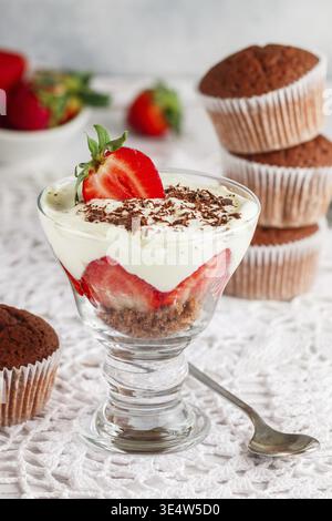 Essen, Kleinigkeiten. Mehrschichtiges Dessert aus Schokoladenschwammkuchen, Schlagsahne oder Ricotta und frischen Erdbeeren in einer Glasschale. Köstliches Gourmet-Frühstück. Stockfoto