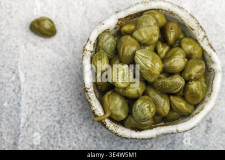 Eingelegte oder gesalzene Kapern in einer Keramikschale in Nahaufnahme. Ungeöffnete Blütenknospen. Köstliche Zutaten für die Küche Mittelmeer, Italienisch, Spanisch, Französisch c Stockfotografie