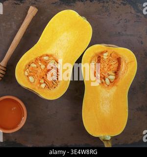 Essen, Hälften rohen Bio-Butternusskürbis auf Backform mit Honig. Selektiver Fokus. Quadratisches Bild. Rustikaler Stil Stockfoto