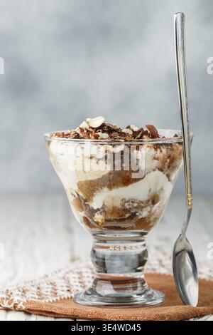 Essen, Kleinigkeiten. Hausgemachtes mehrschichtiges Dessert aus Keks und Frischkäse (Mascarpone oder Joghurt) mit Schokolade und Nüssen im Glas. Tiramisu. Cheesecak Stockfoto