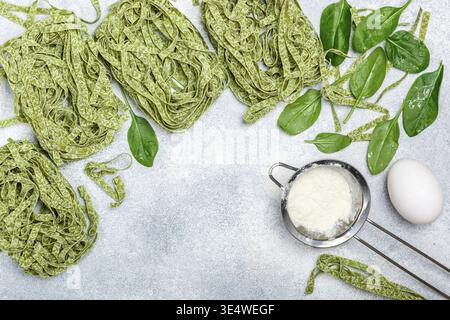 Essen, rohe hausgemachte italienische grüne Pasta Tagliatelle. Trockene Nudeln und Zutaten (Spinat, Mehl, Ei). Selektiver Fokus, Draufsicht, Kopierbereich Stockfoto