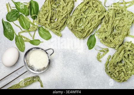 Essen, rohe hausgemachte italienische grüne Pasta Tagliatelle. Trockene Nudeln und Zutaten (Spinat, Mehl, Ei). Selektiver Fokus, Draufsicht, Kopierbereich Stockfoto