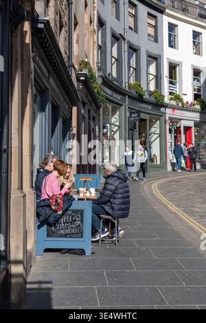 Touristen genießen Essen und Trinken im Sunshine an einem Tisch auf dem Bürgersteig vor einem Café (La Barantine) in der West Bow Street in Edinburgh Stockfoto
