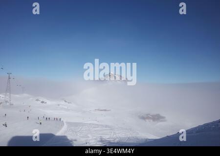 Dieses Foto zeigt ein hochalpines Skigebiet, das von einem Wolkenmeer bedeckt ist, in den Alpen im Swtizerland. Stockfoto