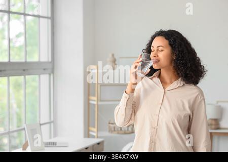 Junge afroamerikanische Frau trinkt zu Hause Wasser Stockfoto
