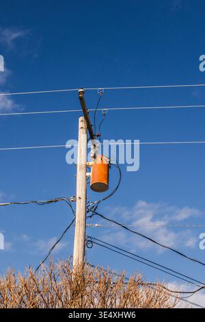 Hölzerner Strommast mit Transformator und Freileitungen vor klarem blauem Himmel in den USA Stockfoto