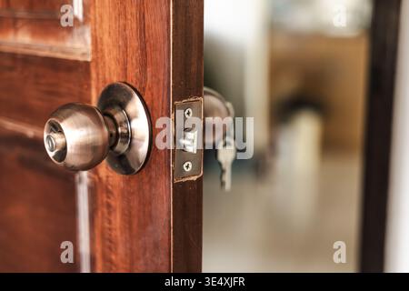 Haustür mit Metall-Türknauf und Schlüssel im Schloss leicht geöffneter Inneneingang Stockfoto