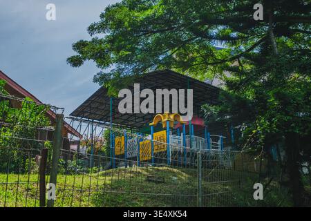 Ein farbenfroher Spielplatz aus Kunststoff und Metall unter einem schützenden Metalldach. Stockfoto