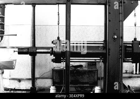 Sloviansk, 1950er-1960er Jahre, Armature-Insulator Plant (AIZ). Detaillierte Archivaufnahme einer schweren industriellen Prüfpresse, die zur Qualitätskontrolle von elektrischen Hochspannungsisolatoren verwendet wird. Das Vintage-Schwarz-weiß-Foto hebt den robusten Stahlrahmen, die Hydraulikzylinder und die komplexe Konstruktion des mechanischen Bohrgeräts hervor. Dieses Bild zeigt die strengen technologischen Standards und Qualitätssicherungsprotokolle in der sowjetischen Fertigung und bewahrt die Maschinengeschichte des friedlichen Donbas. Stockfoto