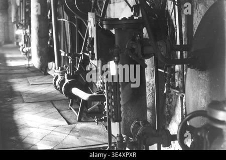 Sloviansk, 1950er-1960er Jahre, Armature-Insulator Plant (AIZ). Detaillierte Archivierungsansicht komplexer Industriemaschinen mit schweren Eisenventilen, Flanschrohren und einem zylindrischen Druckbehälter mit Manometern. Das Schwarzweiß-Foto zeigt die robuste mechanische Infrastruktur und die Flüssigkeitssteuerungssysteme, die hinter den Kulissen in der Keramikfabrik für elektrische Isolatoren arbeiten. Dieses technische Dokument bewahrt das authentische technische Erbe und die industrielle Atmosphäre des friedlichen Donbas. Stockfoto