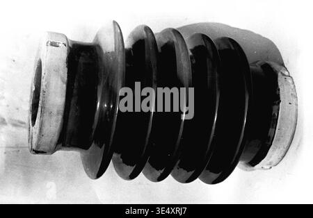 Sloviansk, 1950er-1960er Jahre, Armature-Insulator Plant (AIZ) – Eine detaillierte Nahaufnahme eines robusten, gerippten Keramikisolators, der horizontal liegt. Das Archivbild zeigt deutlich den starken Kontrast zwischen der glänzenden dunklen Industrieglasur und den rohen, unglasierten Montagesenden. Dieses Artefakt dient als Beweis für die strenge Materialwissenschaft, Bautechnik und Präzision, die in der sowjetischen Porzellanherstellung der Mitte des Jahrhunderts erforderlich sind, und dokumentiert die Schwerindustrie im friedlichen Donbass. Stockfoto