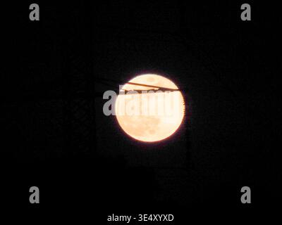 Orangefarbener Vollmond, der hell am dunklen Nachthimmel leuchtet und seine himmlische Schönheit und strukturierte Oberfläche präsentiert, ein Leuchtfeuer im riesigen Universum Stockfoto