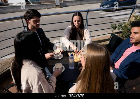Junge Freunde genießen Kaffee und Snacks im Café im Freien Stockfoto
