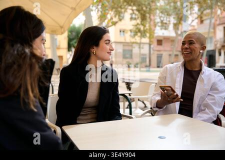 Verschiedene Freundinnen sitzen im Café im Freien und unterhalten sich Stockfoto