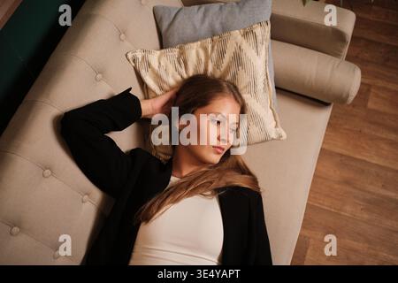 Frau, die auf der Couch ruht und nachdenklich ist Stockfoto