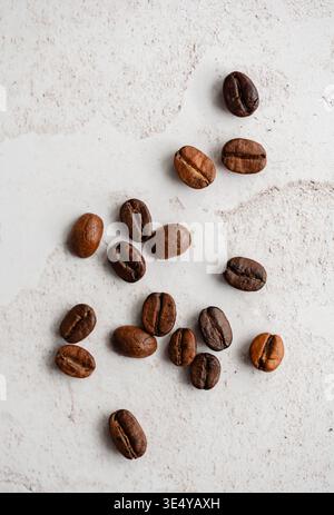 Blick von oben auf ganze geröstete Kaffeebohnen auf hellem Steinhintergrund. Stockfoto