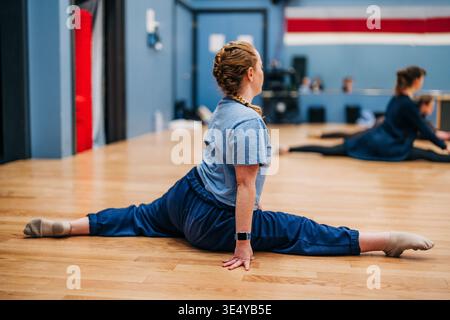 Frau, die im Indoor-Fitness-Studio voll gesplittert ist Stockfoto