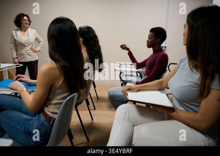Lehrer, der während des Unterrichts verschiedene Schüler in einem Klassenzimmer unterrichtet Stockfoto