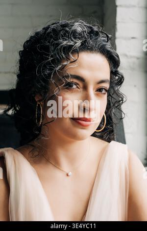 Weiches natürliches Porträt einer Frau mit Locken und Goldschmuck Stockfoto