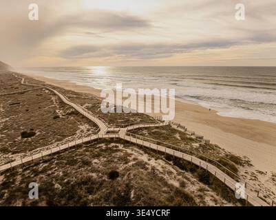 Aus der Vogelperspektive auf einer Holzpromenade, die durch Sanddünen führt und unter einem trüben Himmel zum Meer führt, Kitty Hawk, North Carolina, USA. Stockfoto