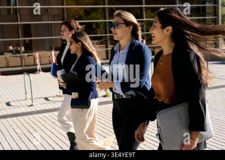 Professionelle Geschäftsfrauen gehen zusammen, lächeln draußen Stockfoto