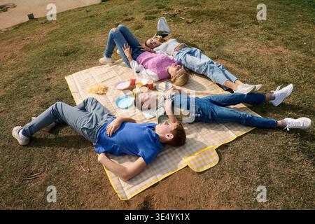 Mutter und drei Kinder entspannen sich draußen auf einer Picknickdecke Stockfoto