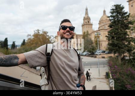 Glücklicher, gutaussehender Hipster-Mann in trendiger Mode-Sonnenbrille mit Rucksack, der in Barcelona reist Stockfoto