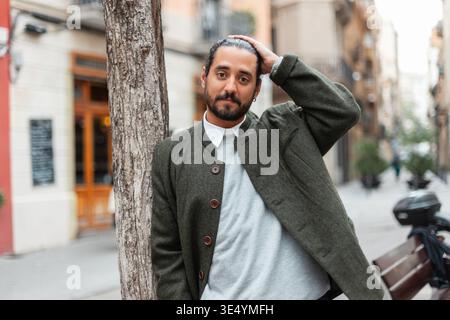 Schöner modischer, stilvoller Mann in stilvoller Kleidung mit Mantel, der auf der Straße in Barcelona spaziert Stockfoto
