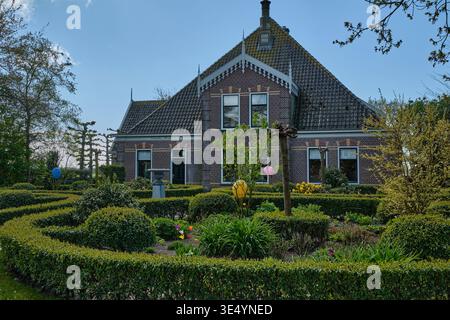 Limmen, Niederlande - 20. April 2025: Niederländisches Erbe und Gartendesign traditionelles Bauernhaus mit Zierhecken und Osterdekoration in Limmen N Stockfoto