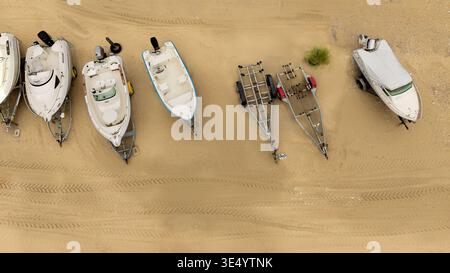 Aus der Vogelperspektive sehen Sie verschiedene Boote, die auf dem Sandstrand ruhen, ihre Formen bilden ein geometrisches Tableau vor dem strukturierten Boden, Fort-Mahon-Plage, Hauts Stockfoto