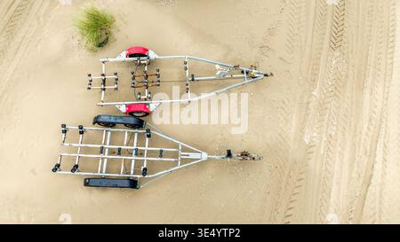 Luftaufnahme von zwei Bootsanhängern am Sandstrand, Reifenspuren um sie herum, Fort-Mahon-Plage, Hauts-de-France, Frankreich. Stockfoto