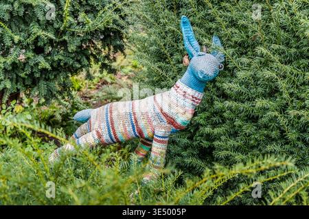 Im Vorgarten des Museums Haniel in Duisburg-Ruhrort steht ein gehäkelter Hirsch inmitten grüner Büsche. An dieser Stelle wurde eine Skulptur eines Hirsches gestohlen und von den Anwohnern durch das Häkeltier ersetzt. Duisburg, Nordrhein-Westfalen, Deutschland Stockfoto