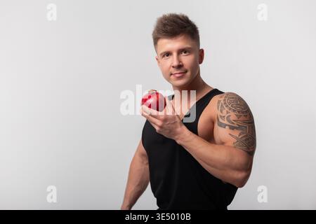 Gutaussehender muskulöser athletischer gesunder Mann, der Granatapfelfrucht hält und in die Kamera blickt. Granatapfelfrucht und Vitamine. Diät Stockfoto