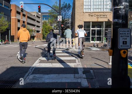 Raleigh, North Carolina, USA – März 2026: Junge Erwachsene fahren mit Elektrorollern über einen Crosswalk im Stadtteil Glenwood South in der Innenstadt von Raleigh. Stockfoto