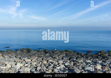 Küstenansicht des Schwarzen Meeres mit Rocky Shore und Cirrus Clouds Eine Weitwinkelaufnahme, die den Übergang von einem felsigen Kieselstrand zur Ruhe zeigt Stockfoto