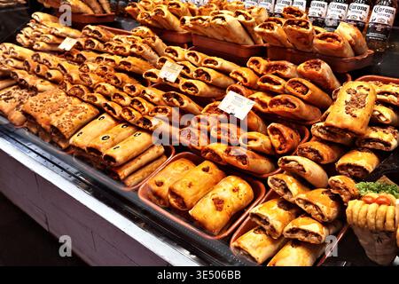 Frisch gebackenes spanisches herzhaftes Gebäck und Empanadas auf dem Marktstand La Boqueria in Barcelona, Spanien, mit Corona-Bierflaschen dahinter. Stockfoto