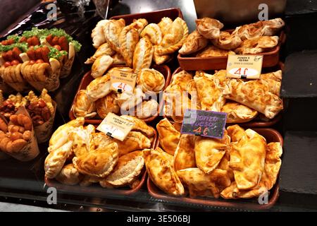 Frisch gebackene Empanadas auf dem La Boqueria Market, Barcelona, mit Preisschildern für Chorizo, Schinken und Käse, Hühnchen & Käse und Spinatfüllungen. Stockfoto