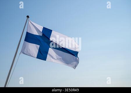 Finnische Nationalflagge winkt auf Fahnenmast vor klarem blauen Himmel finnisches Unabhängigkeitssymbol minimales patriotisches Konzept Stockfoto