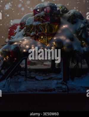 Roter Vintage-Retro-Wagen mit Schnee, Geschenken und Weihnachtsbaum mit Lichtern bei Nacht. Weihnachts- und Neujahrskarte Stockfoto