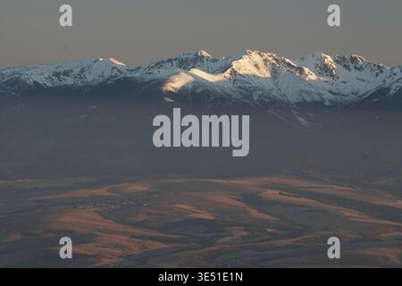 Aus der Vogelperspektive schneebedeckte Gipfel, die von der Sonne geküsst werden und lange Schatten auf die zerklüftete Landschaft werfen, eine ruhige und dennoch beeindruckende aussicht schaffen, Nizke Tatry, Stockfoto