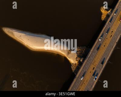 Aus der Vogelperspektive die Poniatowski-Brücke, die sich über die Weichsel erstreckt und lange Schatten auf das Wasser in der Nähe einer Sandinsel in Warschau, Polen, wirft. Stockfoto
