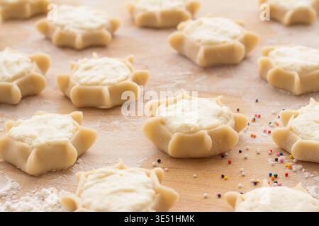 Herstellung von traditionellem italienischem Ricotta-Gebäck auf Holzbrett mit Mehl und bunten Streuseln Stockfoto