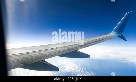 Blick auf die Erde unter dem Flugzeugflügel. Himmelslandschaft aus dem Flugzeugfenster. Reisen und Fliegen zwischen Wolken Stockfoto