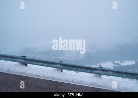Crown Range Summit, Neuseeland: Malerischer Blick auf schneebedeckte Leitplanken und nebelige Berge im Winter am höchsten Punkt des Queenstown Highway. Stockfoto