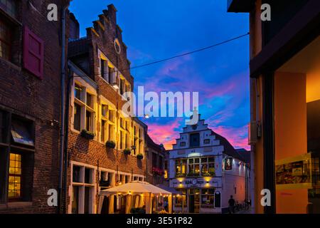 Beleuchtete traditionelle belgische Giebelhäuser und Cafés in einer charmanten, engen Kopfsteinpflasterallee im historischen Patershol-Viertel von Gent Belgien. Stockfoto